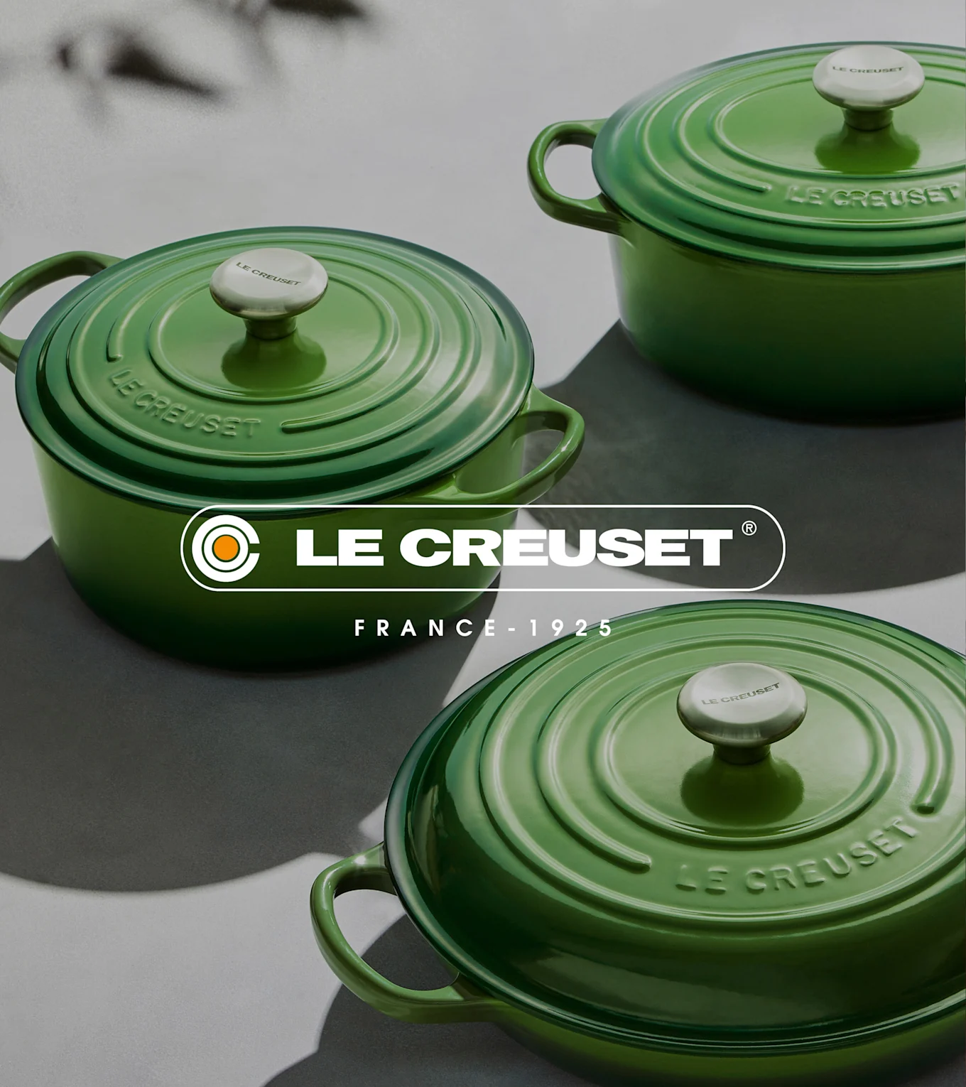 Kolme vihreää Le Creuset valurautaista pyöreää kannellista patapataa harmaalla pinnalla.